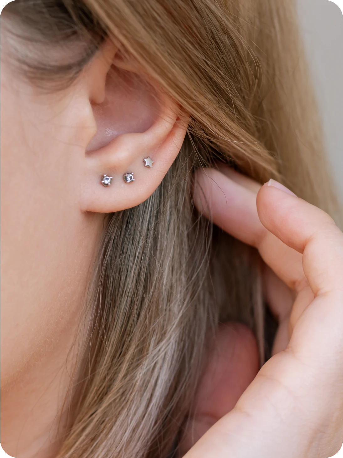 Three silver stud earrings on ear